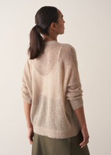 Woman wearing a beige cardigan against a plain background
