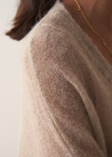 Woman wearing a beige cardigan against a plain background