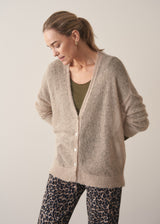 Woman wearing neutral sheer cardigan with. mother of pearl buttons and leopard print barrel leg trousers