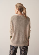 Woman wearing neutral sheer cardigan with. mother of pearl buttons and leopard print barrel leg trousers