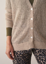 Woman wearing neutral sheer cardigan with. mother of pearl buttons and leopard print barrel leg trousers
