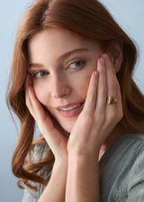 Women wearing a gold hammered heart ring with green blouse