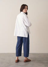 Woman wearing a white boxy shirt and blue jeans