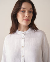 Woman wearing a white linen shirt against a beige background