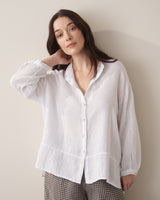 Woman wearing a white linen shirt and checked trousers against a beige background
