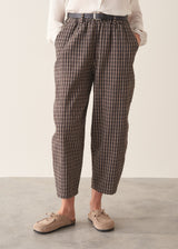 A woman wearing dark brown check barrel leg trousers with a white blouse and matching check jacket