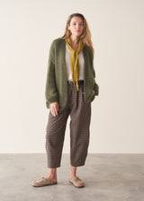 A woman wearing dark brown check barrel leg trousers with a white blouse and matching check jacket