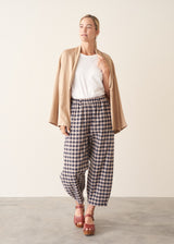 Woman wearing blue and taupe check barrel leg trousers with clog heels and a white t-shirt.