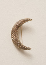 Gold crescent moon brooch on a beige background