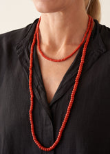 Woman wearing black top and red chunky beaded necklace