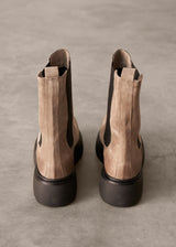 Back view of pair of brown suede ankle boots with black soles on a gray background