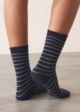 Person wearing midnight blue Neve Socks with a metallic silver stripe and a scalloped ankle detail