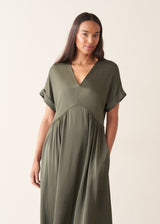A woman wearing a loose, short-sleeve olive green satin maxi dress with a V-neckline