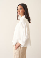 Woman wearing white relaxed boxy shirt and light linen trousers