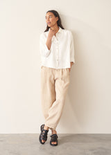 Woman wearing white relaxed boxy shirt and light linen trousers