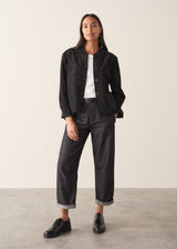 Woman wearing dark blue-black denim jeans, a white t-shirt and black brogues.