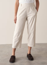 Woman wearing cropped tapered leg cord trousers in oatmeal with blue linen shirt