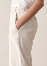 Woman wearing cropped tapered leg cord trousers in oatmeal with blue linen shirt