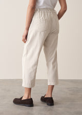 Woman wearing cropped tapered leg cord trousers in oatmeal with blue linen shirt