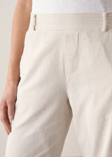 Woman wearing cropped tapered leg cord trousers in oatmeal with blue linen shirt