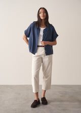 Woman wearing cropped tapered leg cord trousers in oatmeal with blue linen shirt