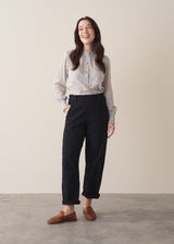 Woman wearing black denim trousers and a white stripe shirt