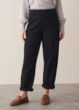 Woman wearing black denim trousers and a white stripe shirt