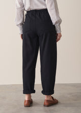 Woman wearing black denim trousers and a white stripe shirt