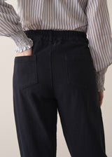 Woman wearing black denim trousers and a white stripe shirt