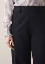 Woman wearing black denim trousers and a white stripe shirt
