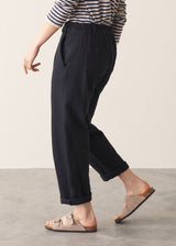 Woman wearing black tapered leg jeans, sandals and a dark stripe sweater