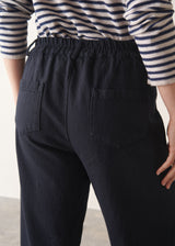 Woman wearing black tapered leg jeans, sandals and a dark stripe sweater
