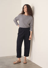 Woman wearing black tapered leg jeans, sandals and a dark stripe sweater