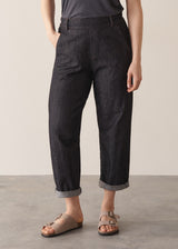 Woman wearing grey sleeveless vest and dark blue black tapered denim jeans