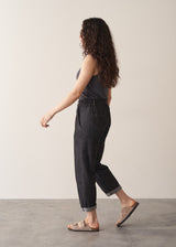 Woman wearing grey sleeveless vest and dark blue black tapered denim jeans