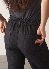 Woman wearing grey sleeveless vest and dark blue black tapered denim jeans