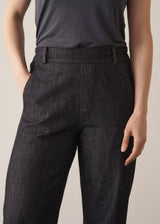 Woman wearing grey sleeveless vest and dark blue black tapered denim jeans