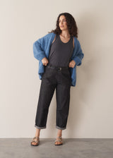 Woman wearing grey sleeveless vest and dark blue black tapered denim jeans