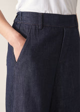 Woman wearing dark blue tapered denim trousers, a white vest top and leopard print loafers