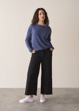 Woman wearing a cornflower blue knit sweater with black wide leg trousers