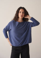 Woman wearing a cornflower blue knit sweater with black wide leg trousers