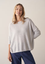 Woman wearing grey relaxed sweater with blue barrel leg jeans