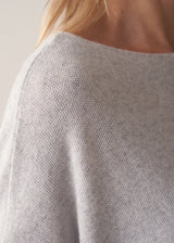 Woman wearing grey relaxed sweater with blue barrel leg jeans