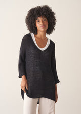 Woman wearing oversized black sweater with off white jeans and black sandals.