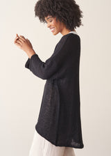 Woman wearing oversized black sweater with off white jeans and black sandals.