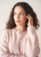 Woman wearing light blush pink button up cardigan with blue jeans