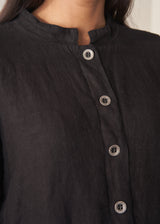 Woman wearing black boxy linen jacket with metal buttons