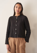 Woman wearing black boxy linen jacket with metal buttons