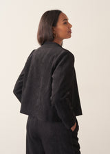 Woman wearing plush herringbone cropped jacket iwth matching trousers and a white top