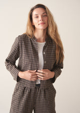 A woman wearing a dark brown check cropped jacket with matching barrel leg trousers and a white t-shirt